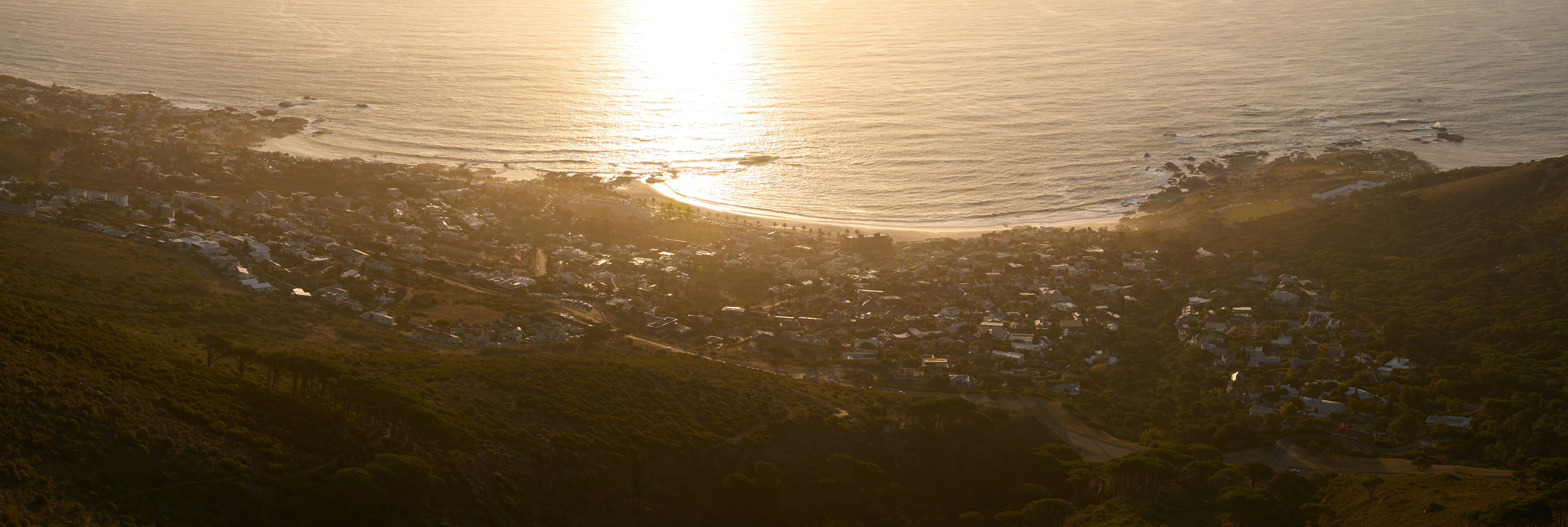 the sun is setting over a city on a hill
