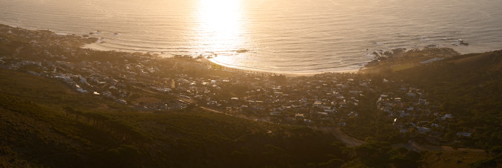 the sun is setting over a city on a hill