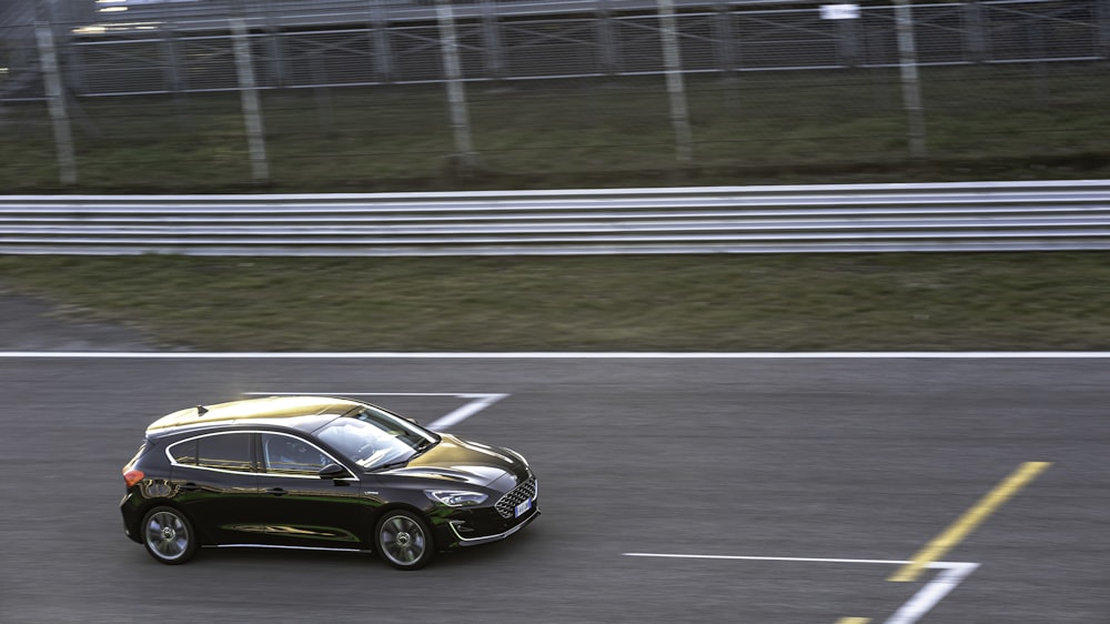 a black car driving down a race track