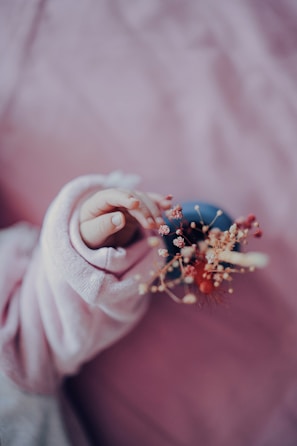 a baby's hand holding a tiny flower