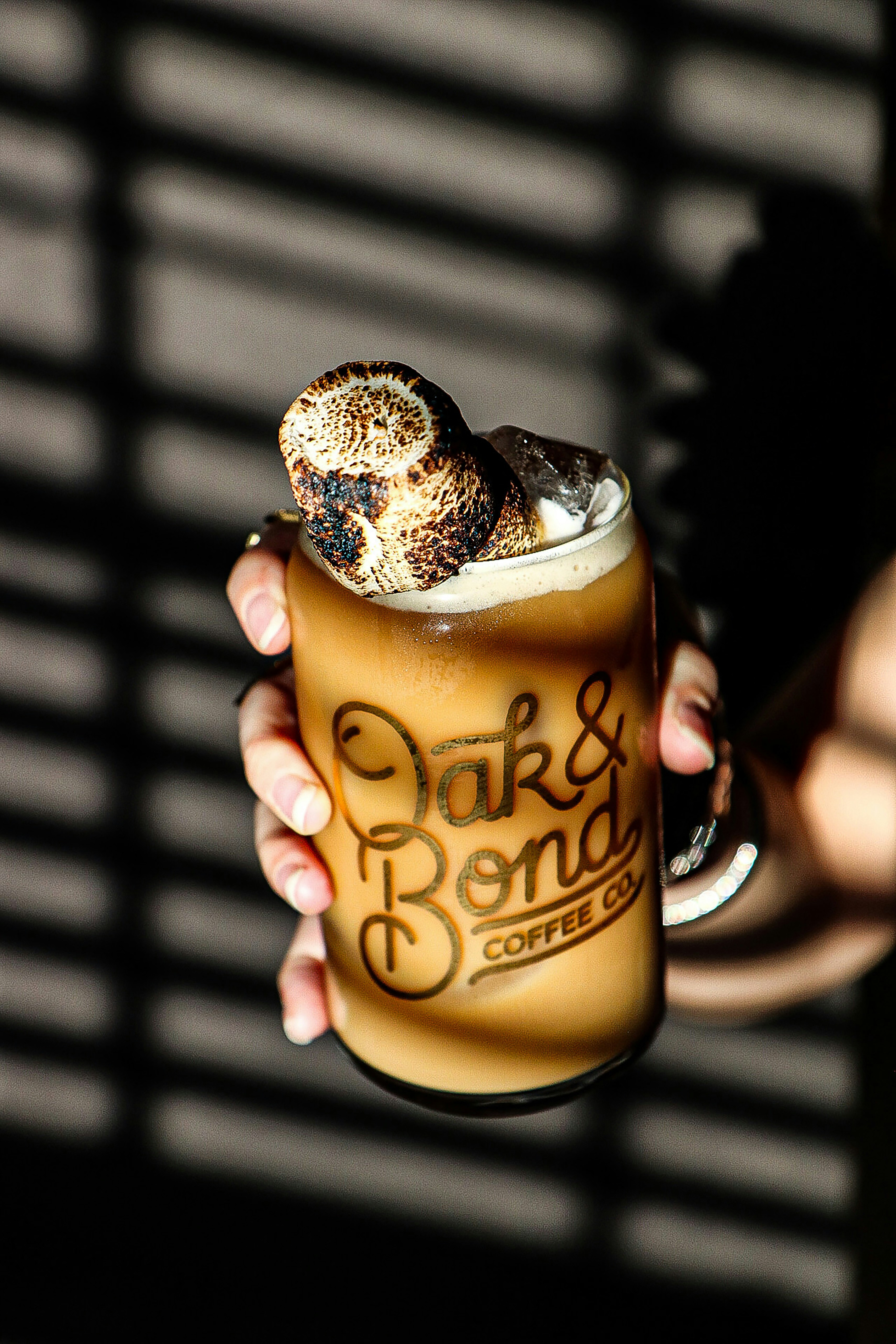 a person holding a drink with a donut on top of it