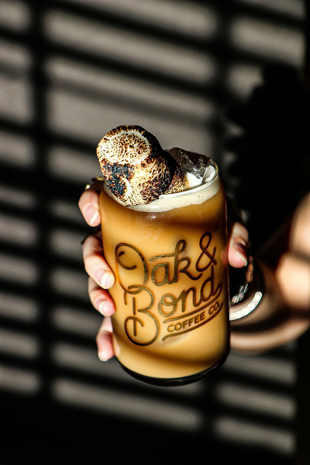 a person holding a drink with a donut on top of it