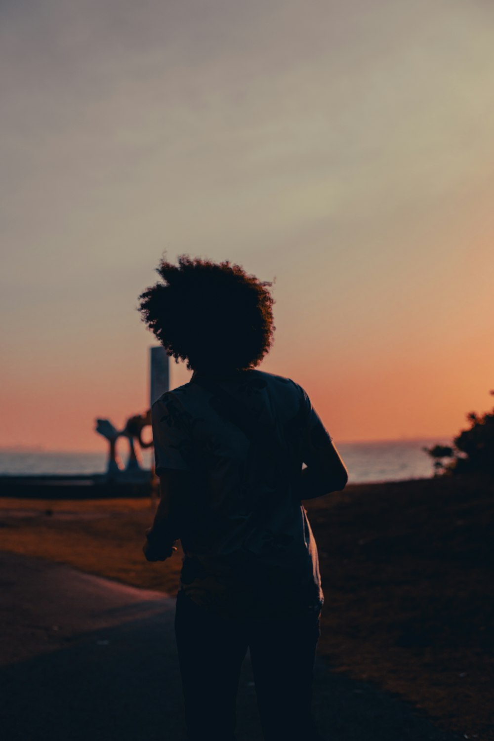 a person standing on a sidewalk near the ocean