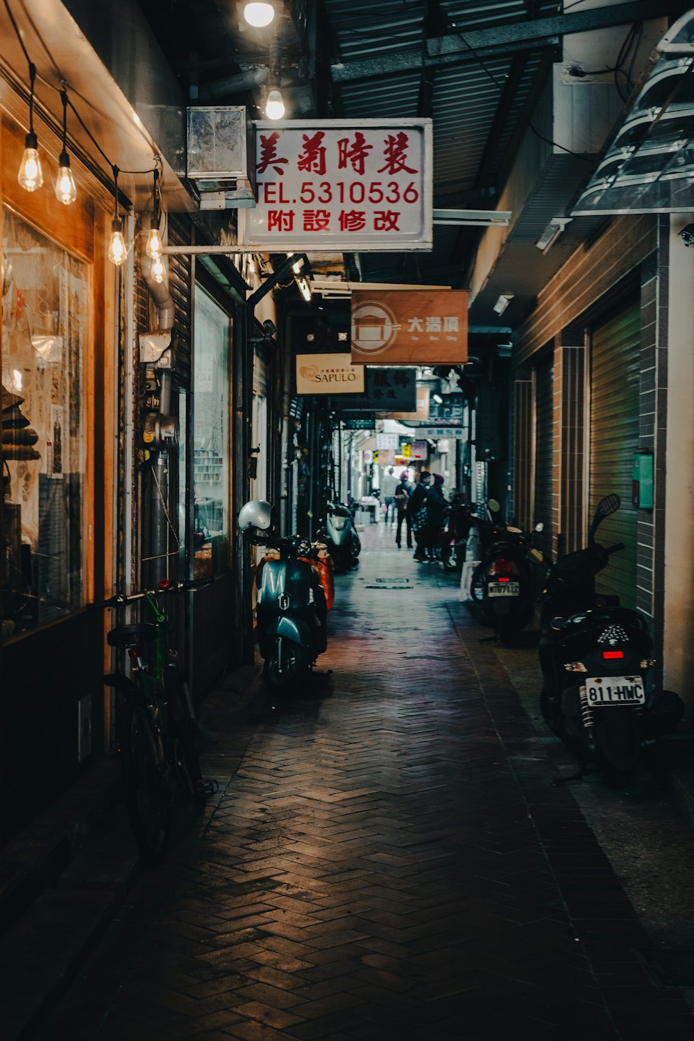 a narrow city street with a few motorcycles parked on the side of it