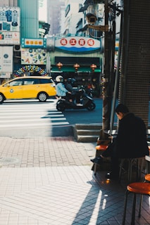 A vibrant city street scene showing a Big Giant Rides motorcycle taxi weaving through traffic with a happy passenger.