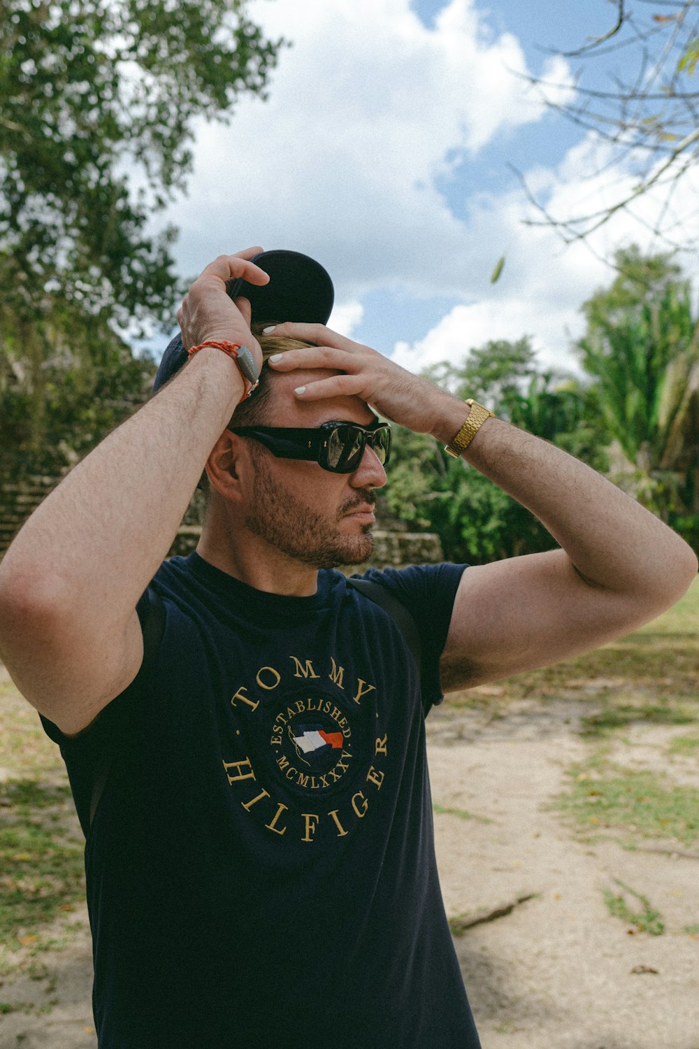 a man in a black shirt and sunglasses holding a hat