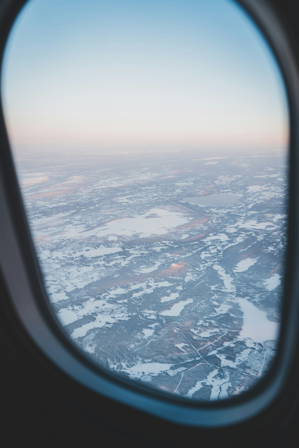 an airplane window looking out on a snowy landscape