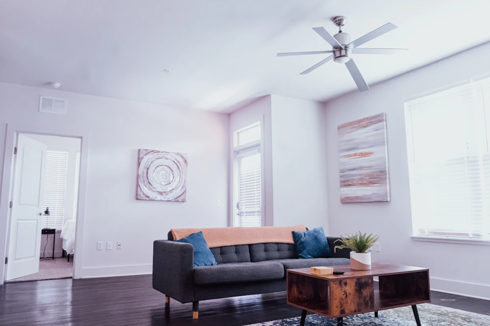 Gray sofa sits against white-painted wall with natural light pouring through two windows upstairs