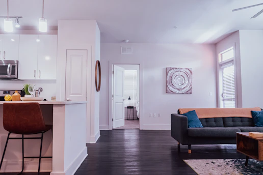A friendly agent showing a modern apartment to a young couple in a bright living room.