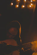 Person practicing guitar chords in a cozy room