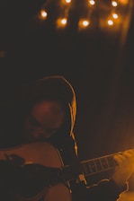 A student playing acoustic guitar in a cozy music studio.