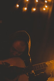 A student playing acoustic guitar in a cozy music studio.