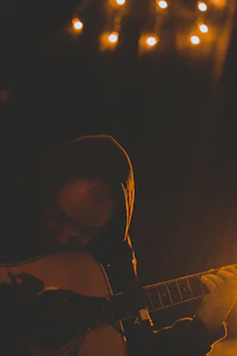 Dominic Holmes strumming his guitar passionately on a cozy pub stage under warm lights.