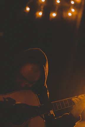 A person strumming an acoustic guitar in a cozy room