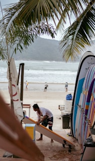 a man working on a surfboard at the beach