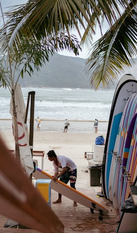 a man working on a surfboard at the beach
