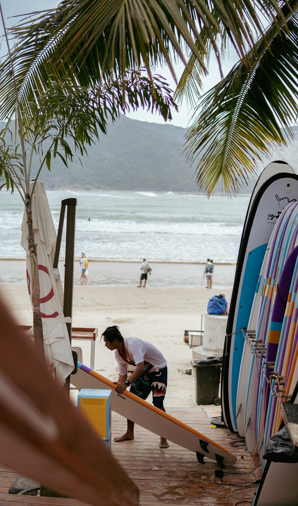 a man working on a surfboard at the beach