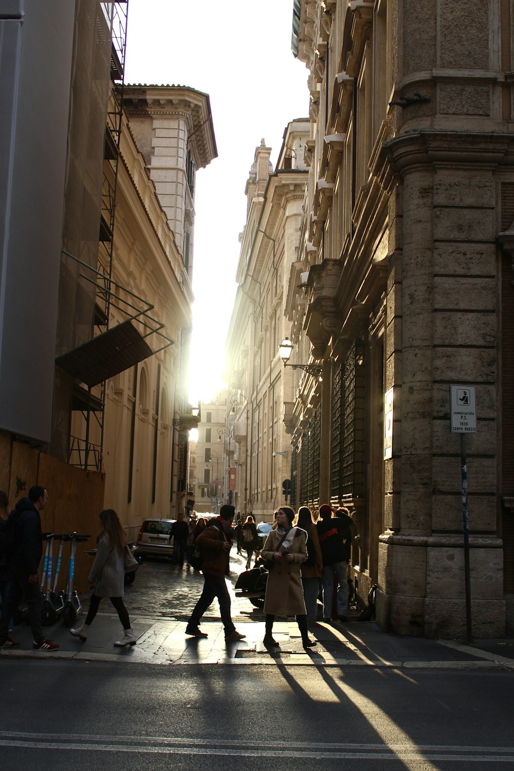 a group of people walking down a street next to tall buildings