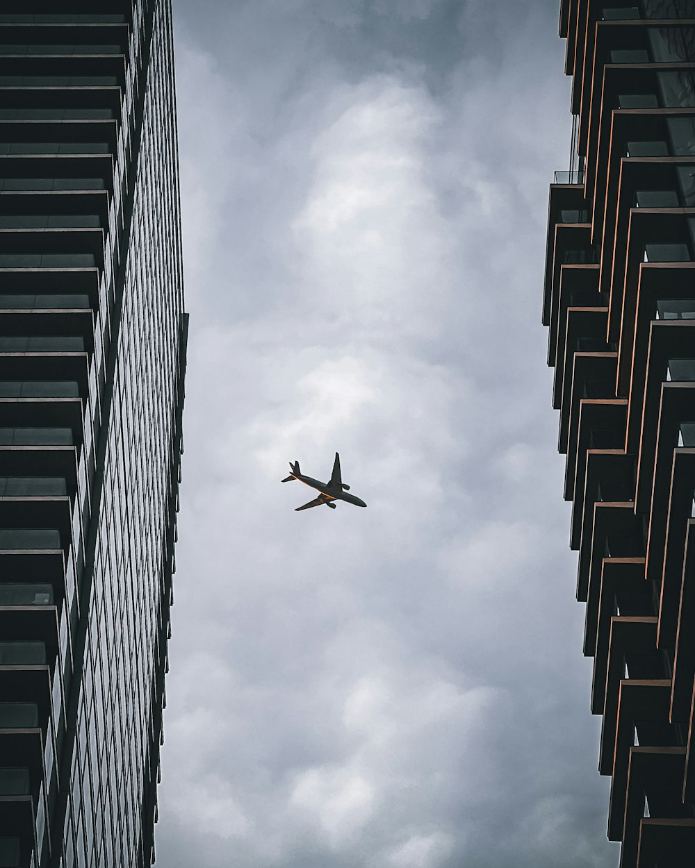 an airplane flying in the sky between two tall buildings