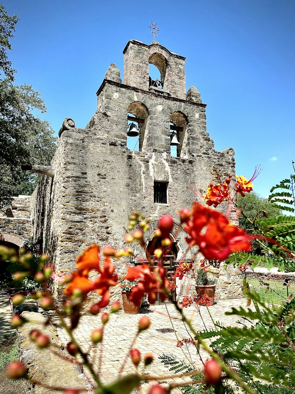 a stone building with a bell tower and flowers in the foreground