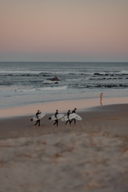 A group of surfers laughing and sharing stories near the shoreline.