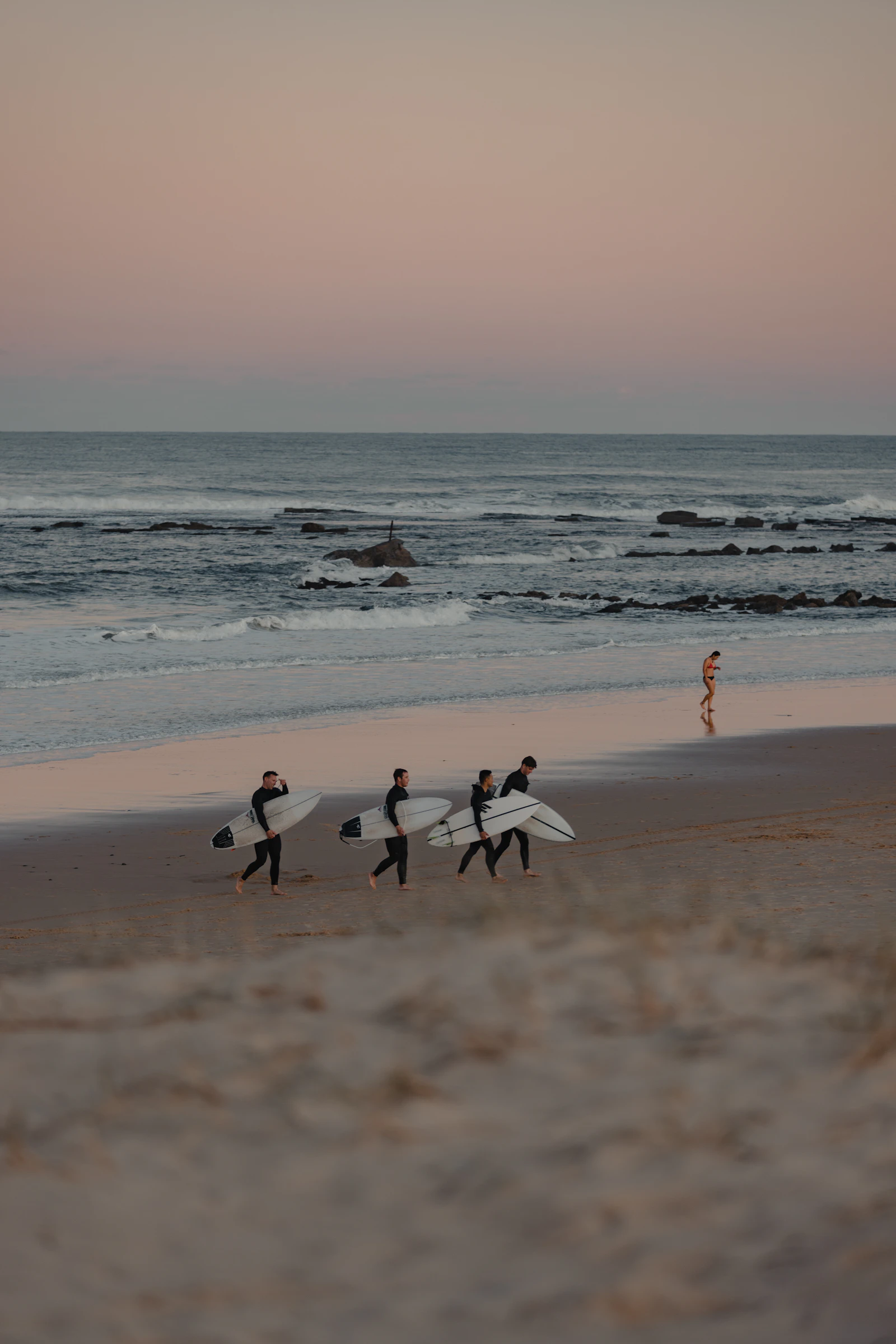 Group walking on the beach with surfboards