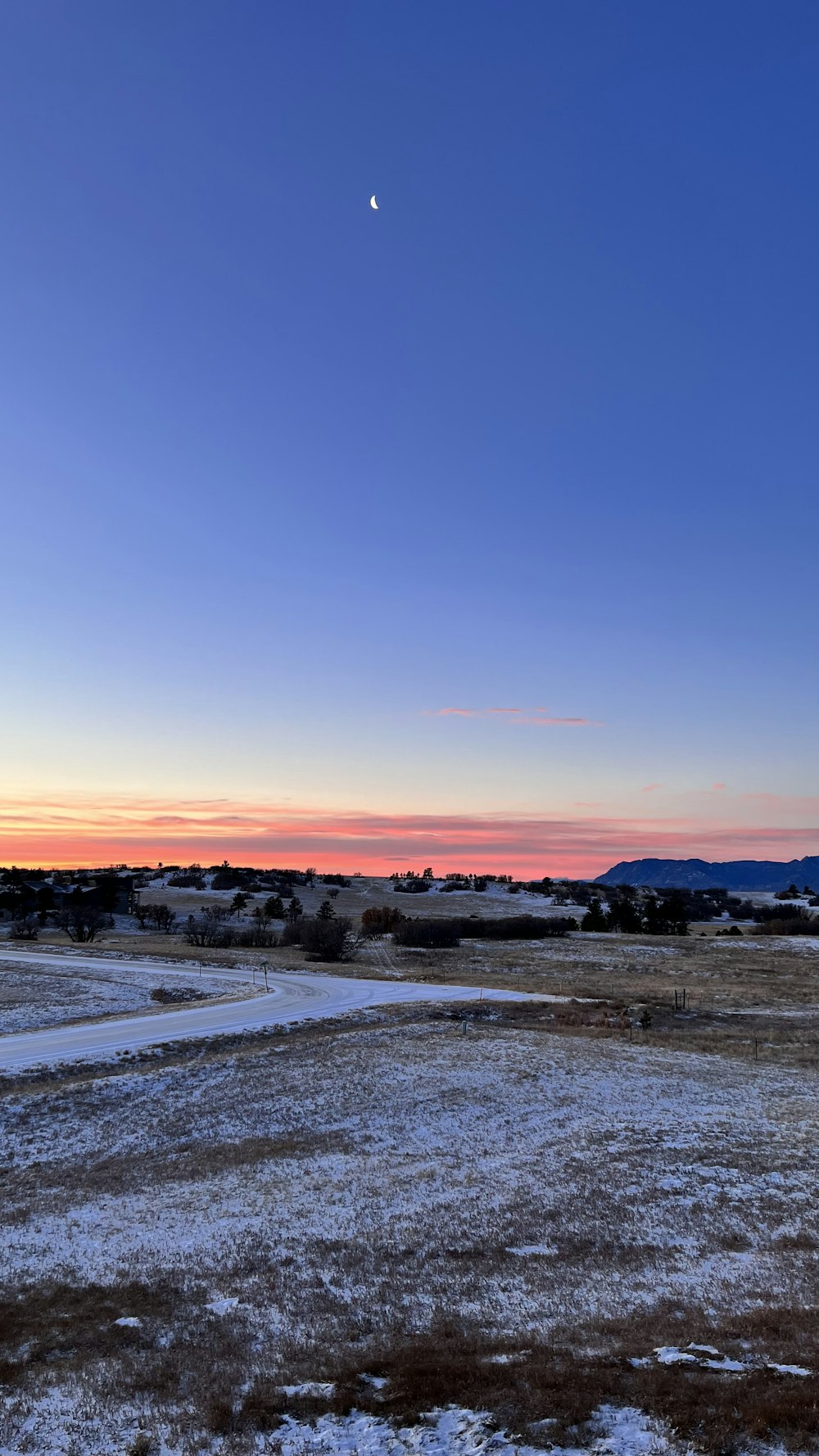 the sun is setting over a snowy field