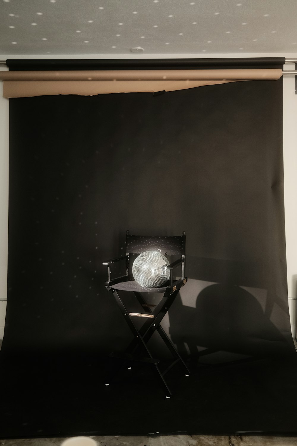 a black and white photo of a chair in front of a black backdrop