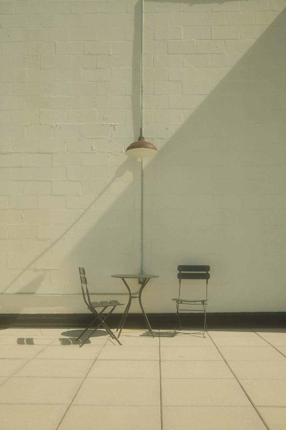two chairs and a table in front of a white brick wall