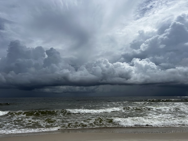 Storm clouds gathering over a rugged coastline with crashing waves.