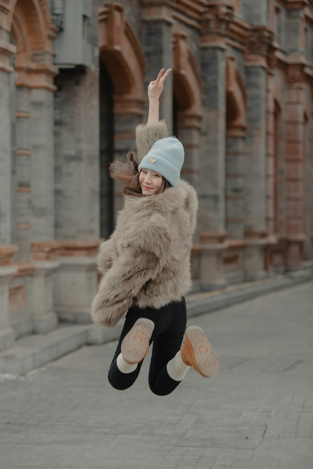 a woman in a fur coat is jumping in the air