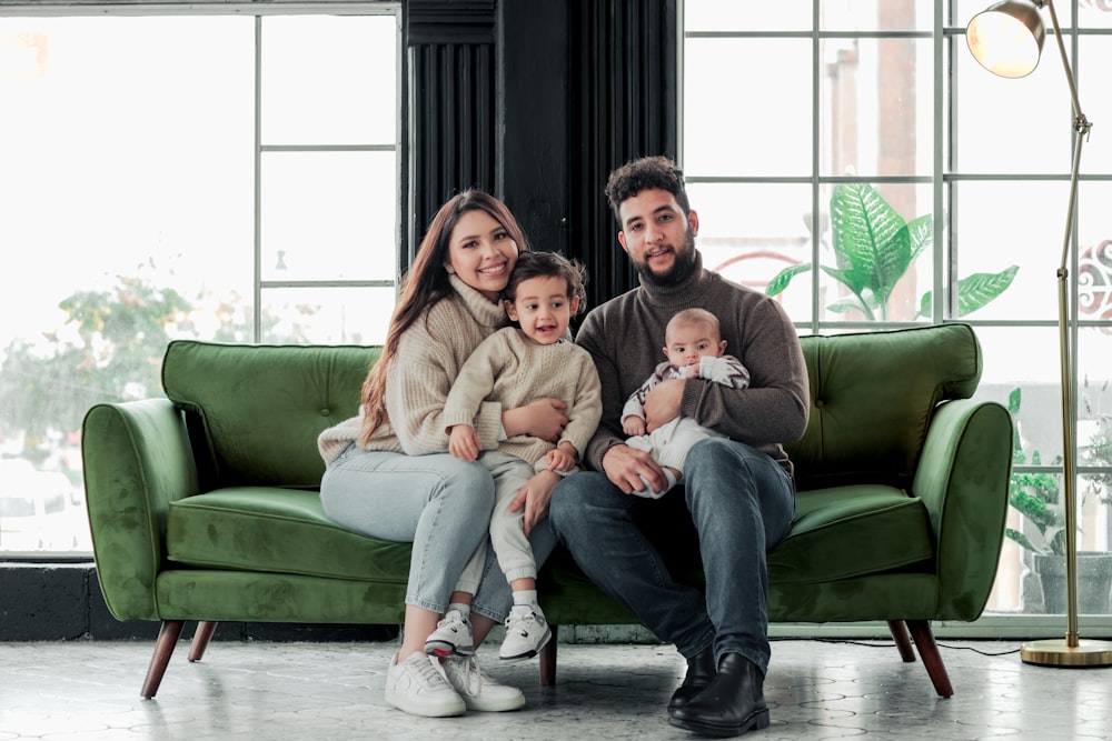 a family sitting on a green couch in a living room