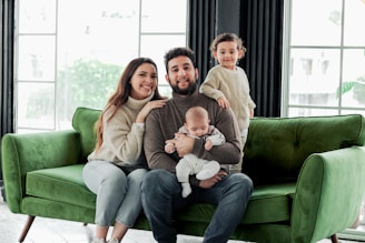 a family sitting on a green couch in a living room