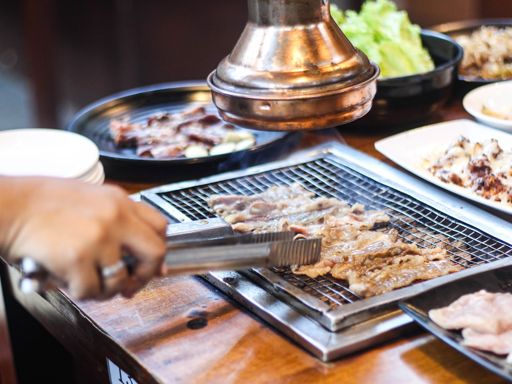 사람이 그릴에 고기를 굽고 있다