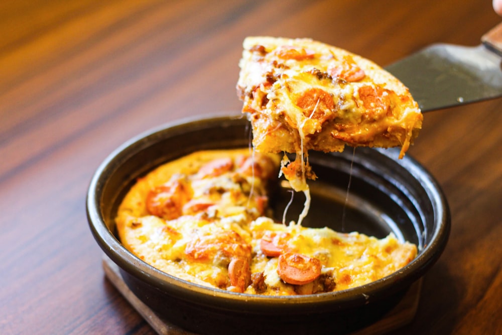 a person taking a slice of pizza from a pan