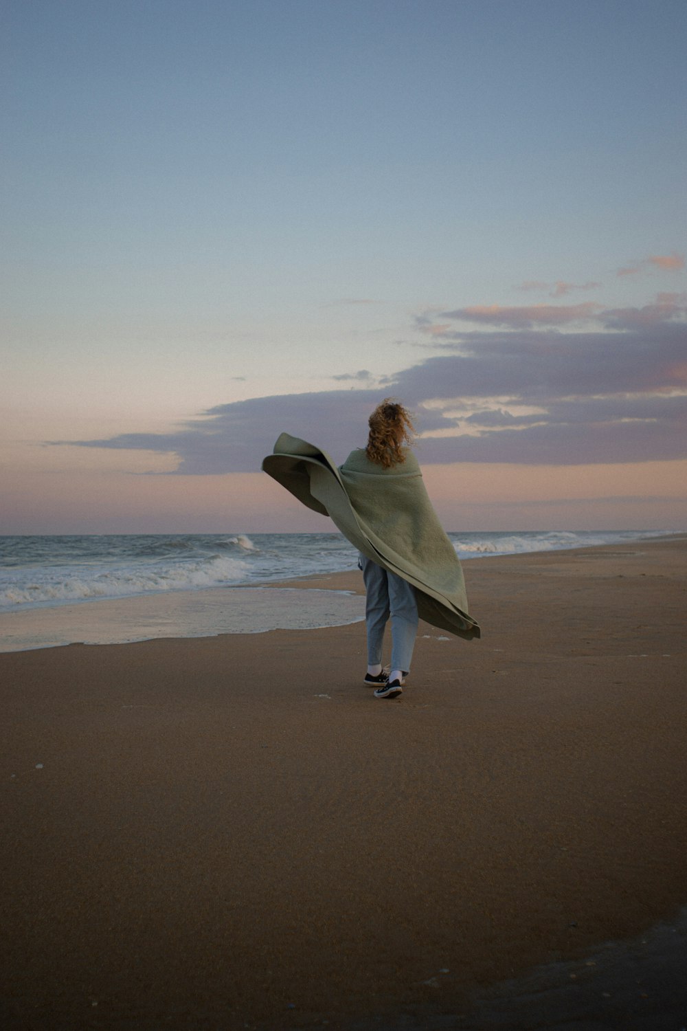 a person walking on a beach with a surfboard