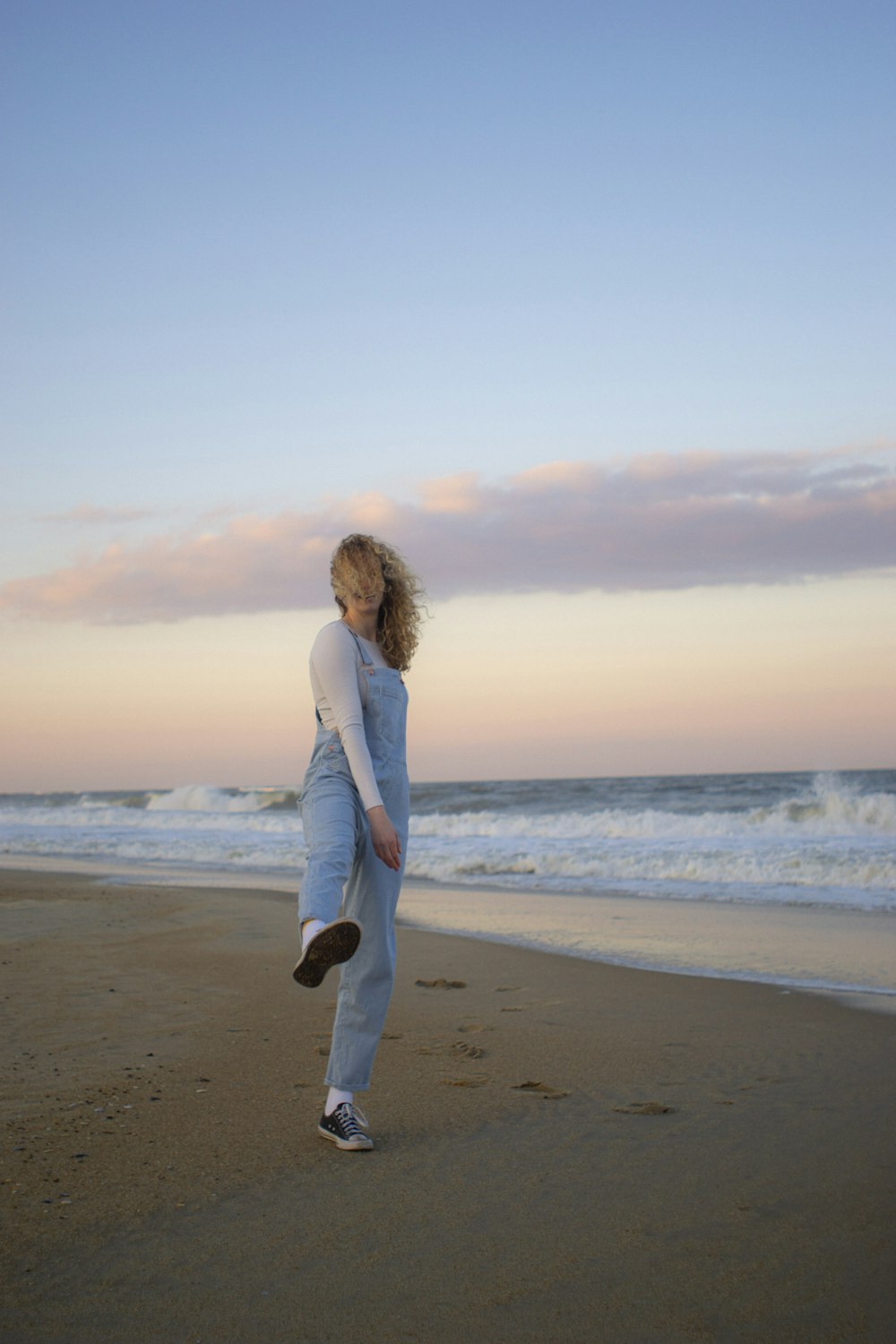 a woman standing on top of a sandy beach next to the ocean