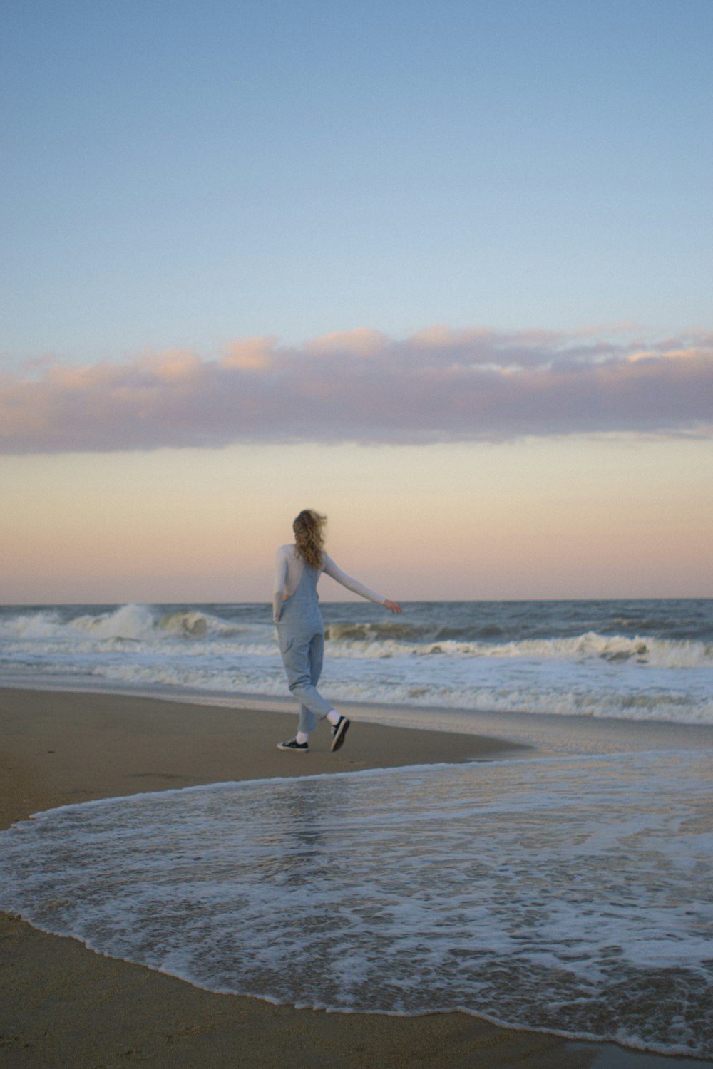 a woman is running on the beach with a frisbee