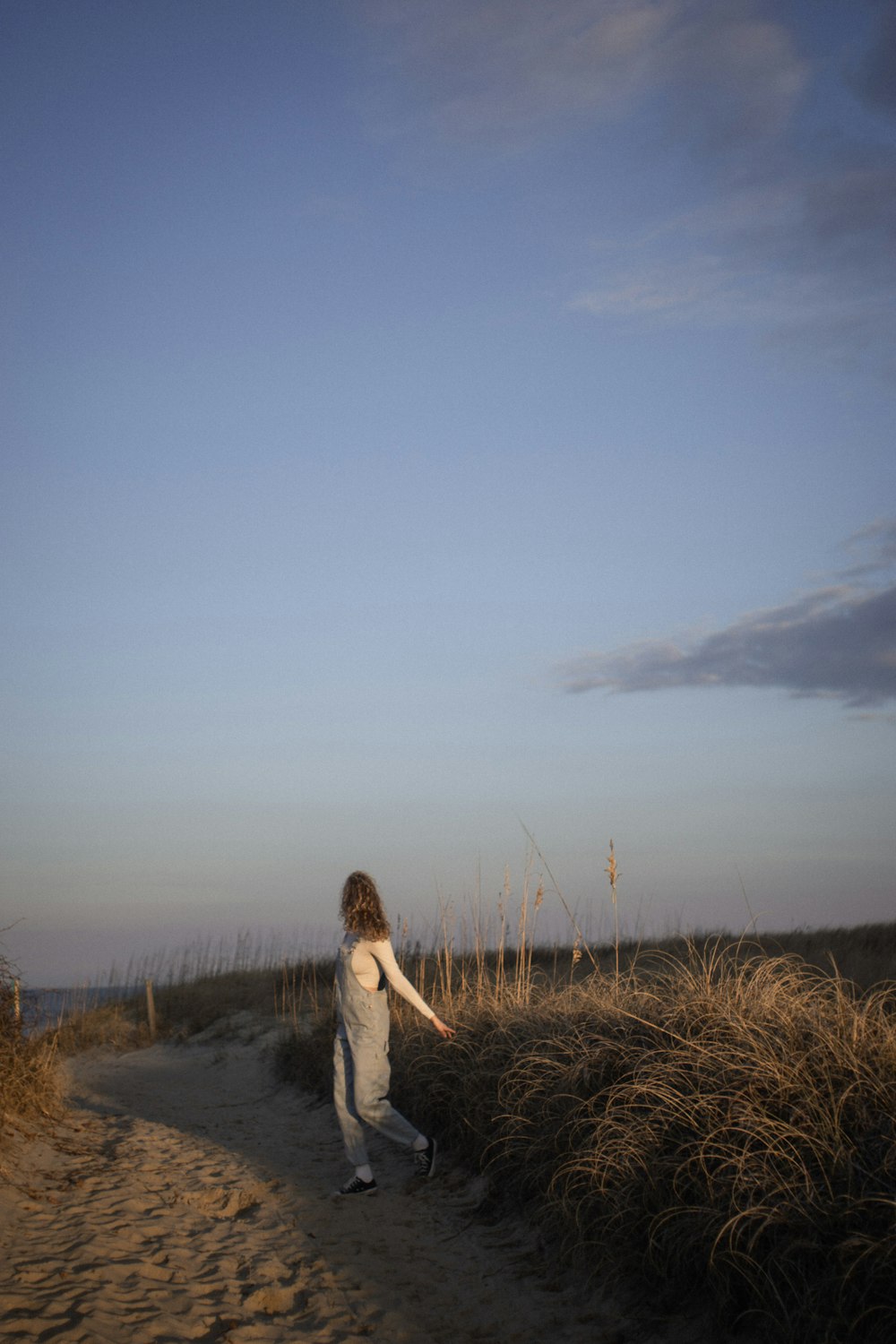 a woman in a white dress is walking down a path