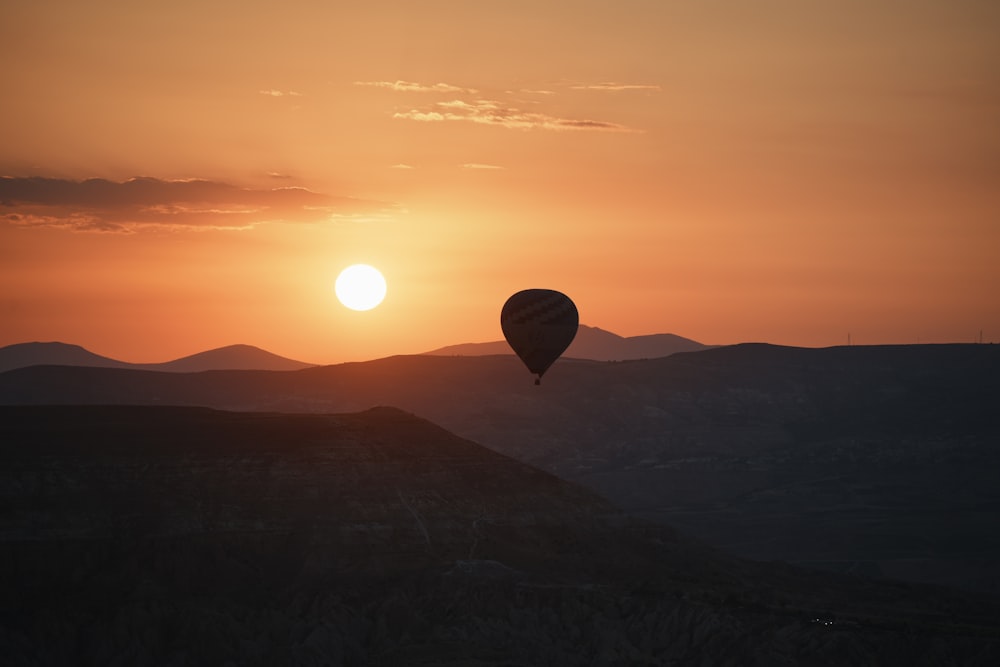 a hot air balloon flying in the sky at sunset