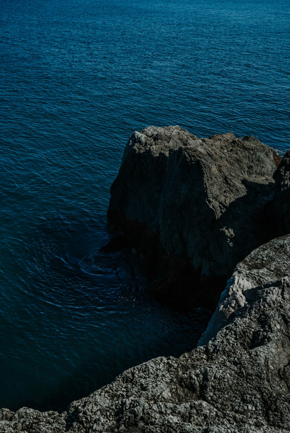 a person sitting on a rock near the ocean