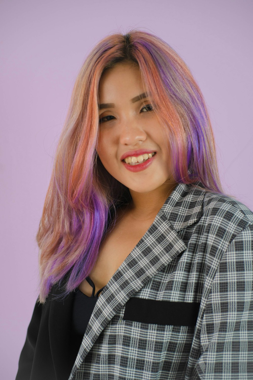 a woman with pink hair and a plaid jacket