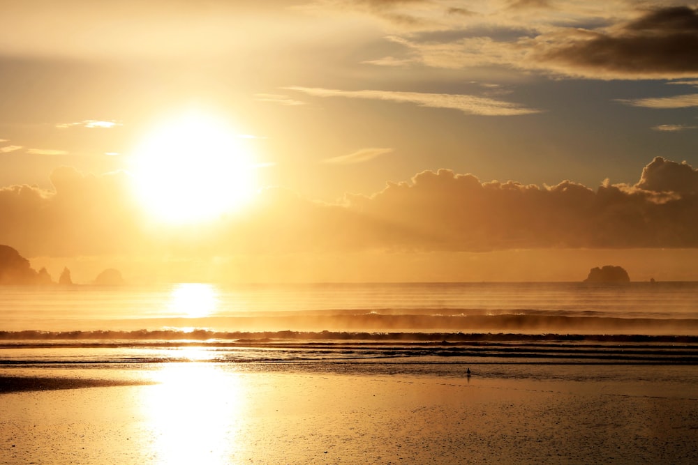 the sun is setting over the ocean on the beach