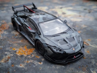 Sleek black diecast muscle car model displayed on a reflective surface with subtle lighting highlighting its curves