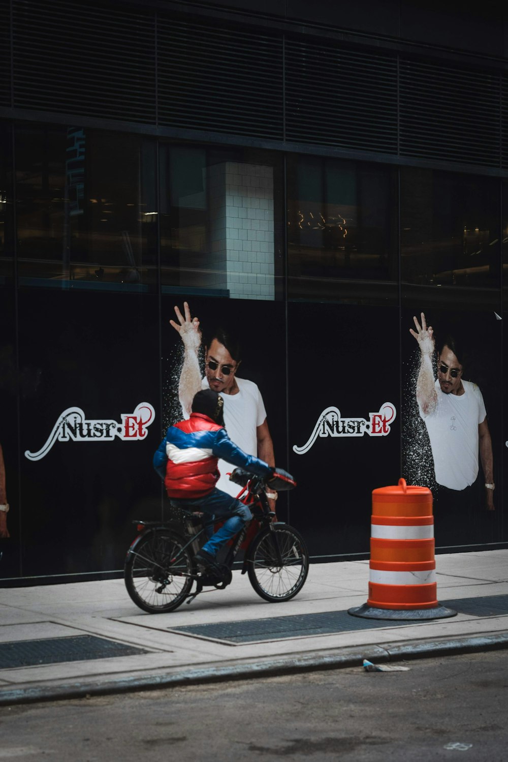 a man riding a bike down a street next to a traffic cone