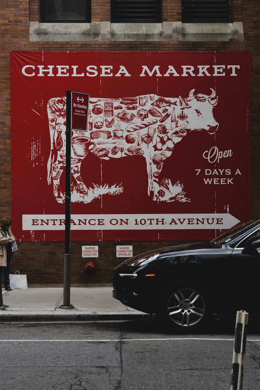 a woman walking down a street past a cow advertisement