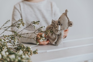 Close-up of a child's hand holding a teddy bear in a preschool setting.