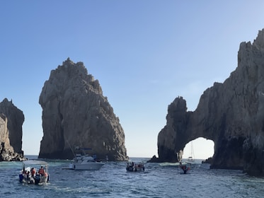 Boat approaching the famous Arch of Cabo San Lucas under a clear blue sky.
