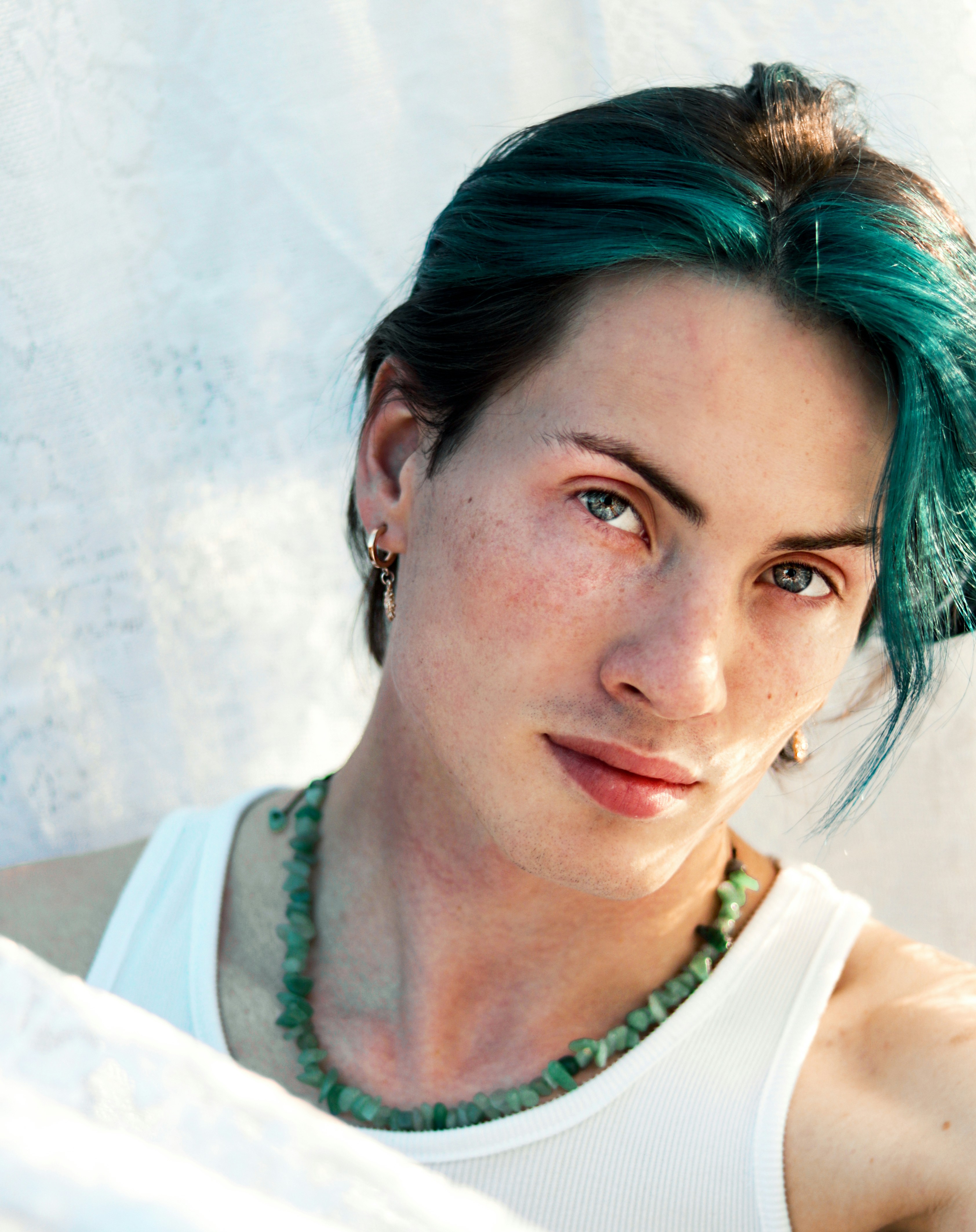 A woman with green hair wearing a white tank top