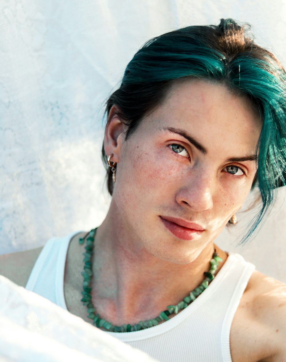 a woman with green hair wearing a white tank top